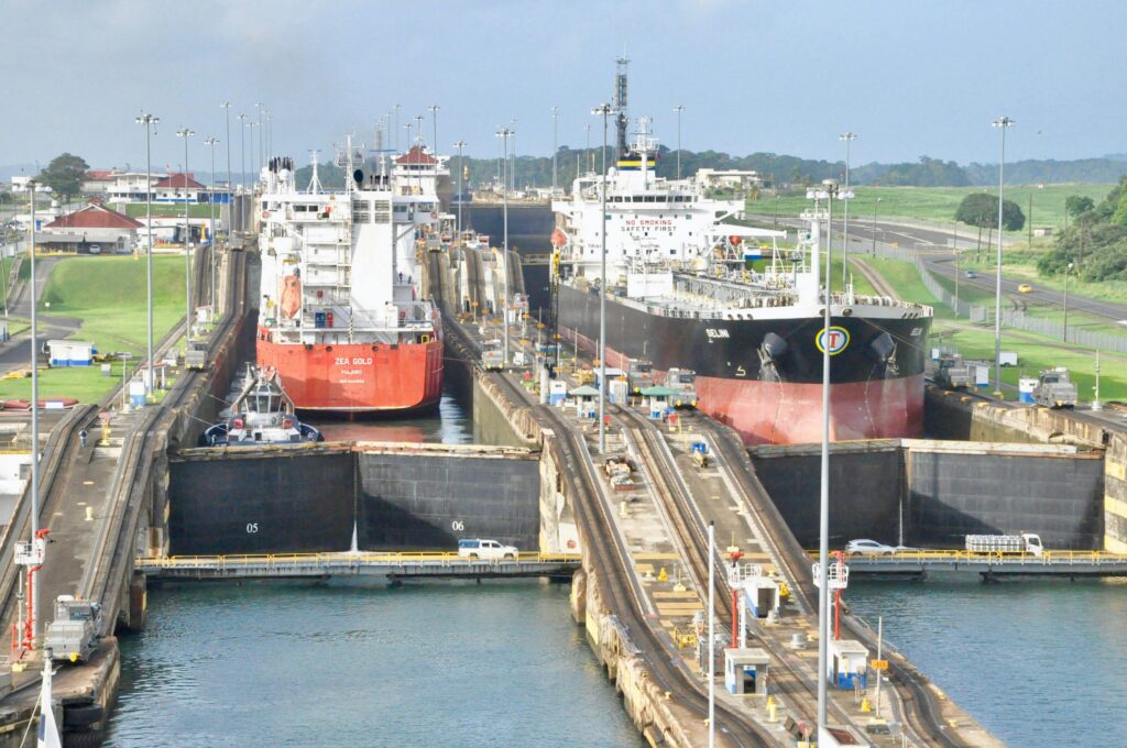 Cargo ships navigating the Panama Canal Miraflores Locks on a clear day, showcasing a bustling transportation hub.
