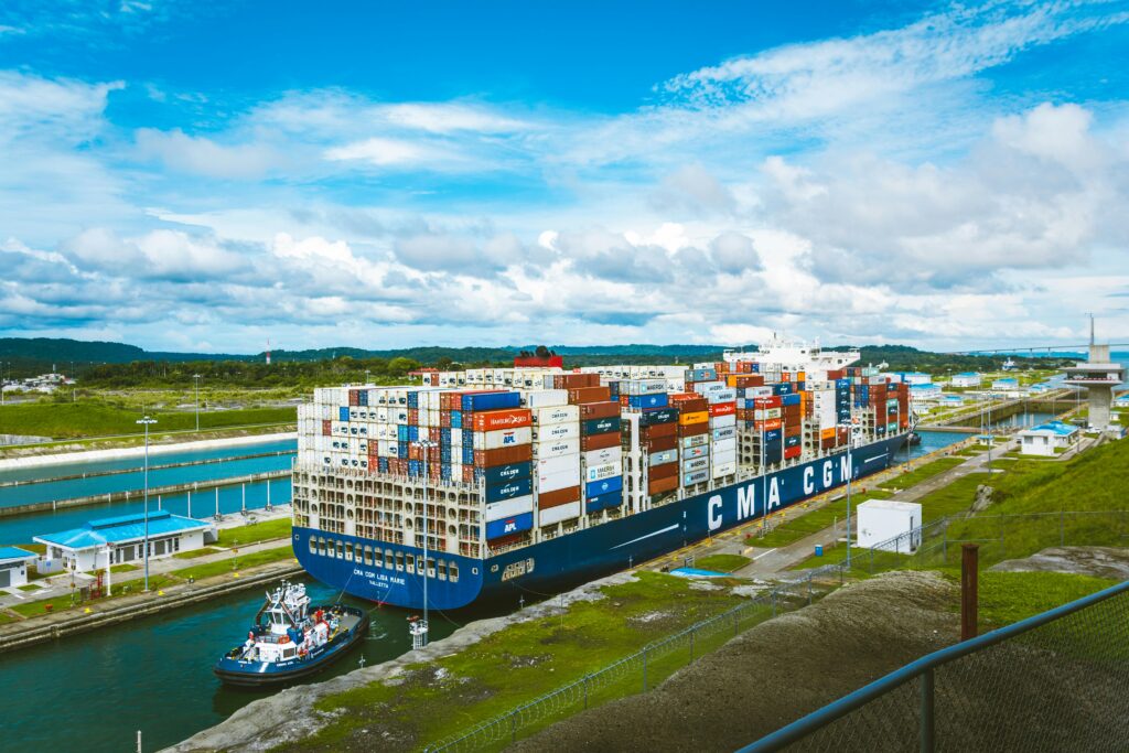 A vast cargo ship passes through the Panama Canal on a bright day, showcasing global trade and its importance to US maritime cargo.