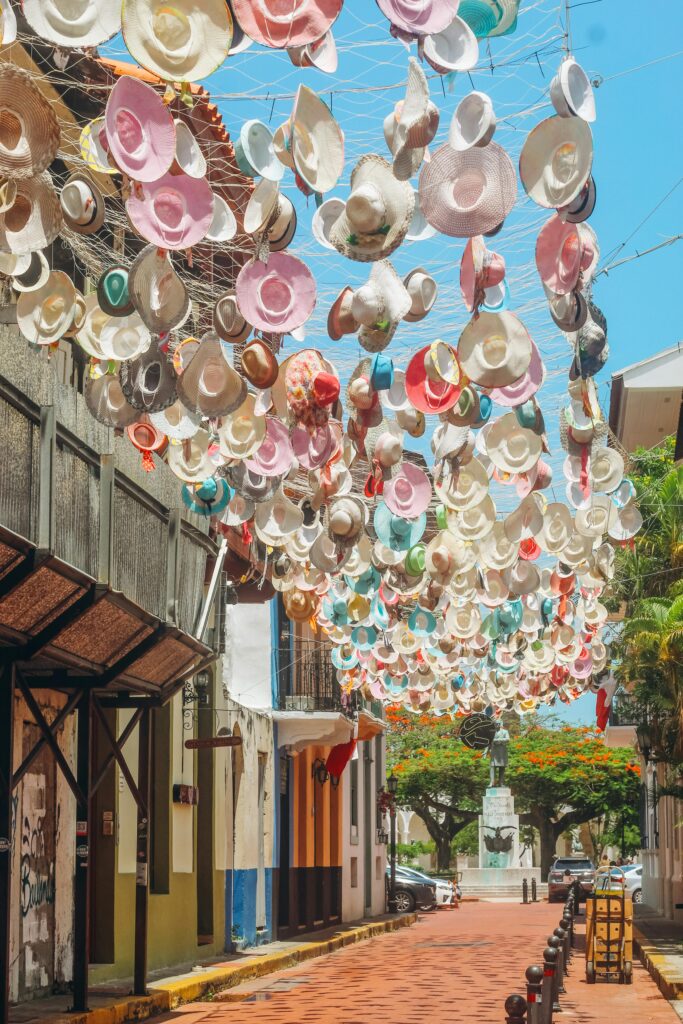 Vibrant street art display of hanging hats under a clear blue sky in Casco Viejo, Panama City.
